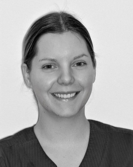 Leende tandsköterska med uppsatt hår, fotograferad i svartvitt mot en ljus bakgrund.