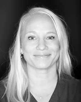 Porträtt av en leende kvinnlig tandläkare med långt blont hår.