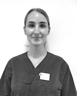 Leende tandhygienist med uppsatt hår, fotograferad i svartvitt mot en ljus bakgrund.