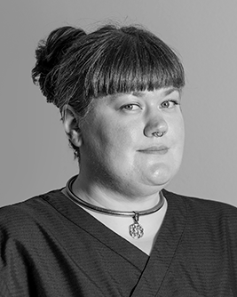 Porträtt av en tandhygienist med uppsatt hår och lugg, fotograferad mot en neutral bakgrund.