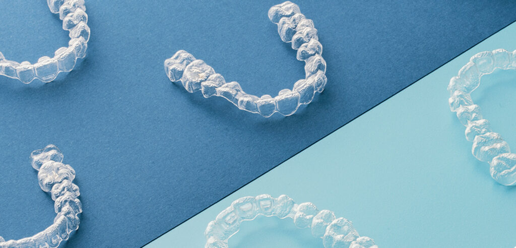 Genomskinliga Invisalign-skenor på blå bakgrund – används för diskret tandreglering med aligners.