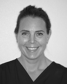 Leende kvinnlig tandläkare med mörkt uppsatt hår.