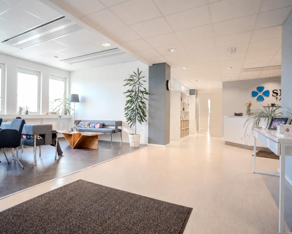 Väntrum på Smile Tandvård med svarta stolar och stora fönster som erbjuder en ljus och rymlig atmosfär med utsikt över staden.