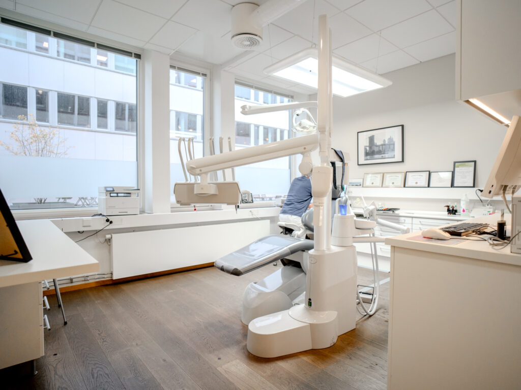 Bild av ett behandlingsrum på Smile Göteborg Avenyn med en tandläkarstol, stort fönster och modern utrustning i ett ljust utrymme.