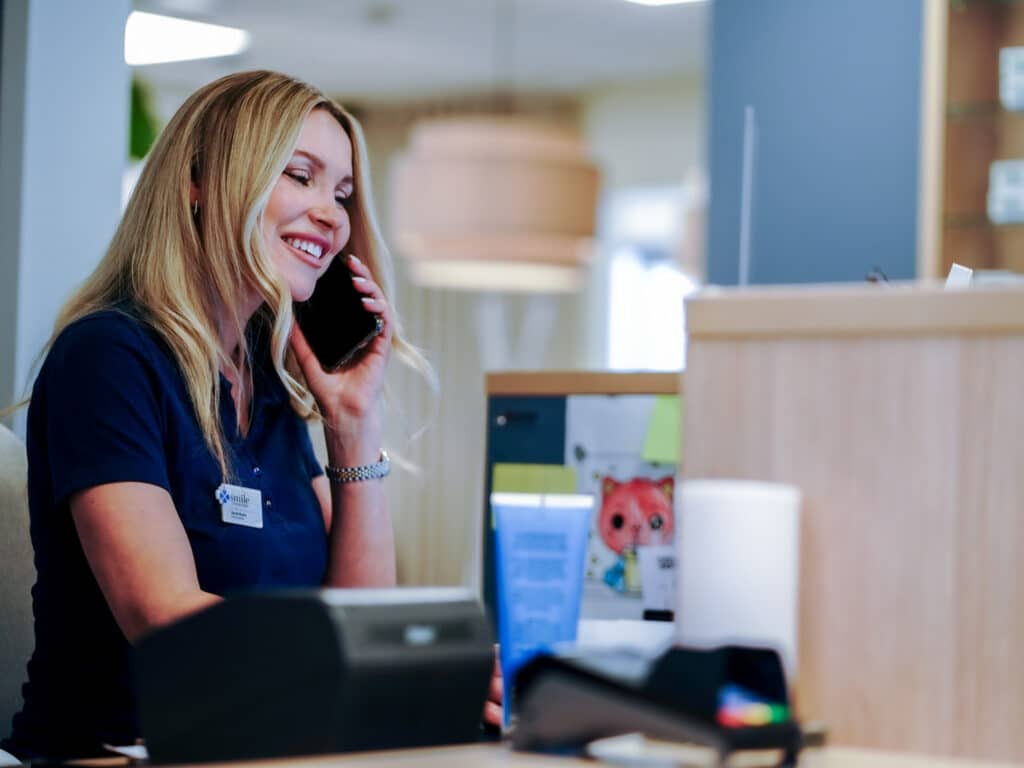 Medarbetare i receptionen på Smile Tandvård Hagastaden, Vasastan, pratar i telefon.
