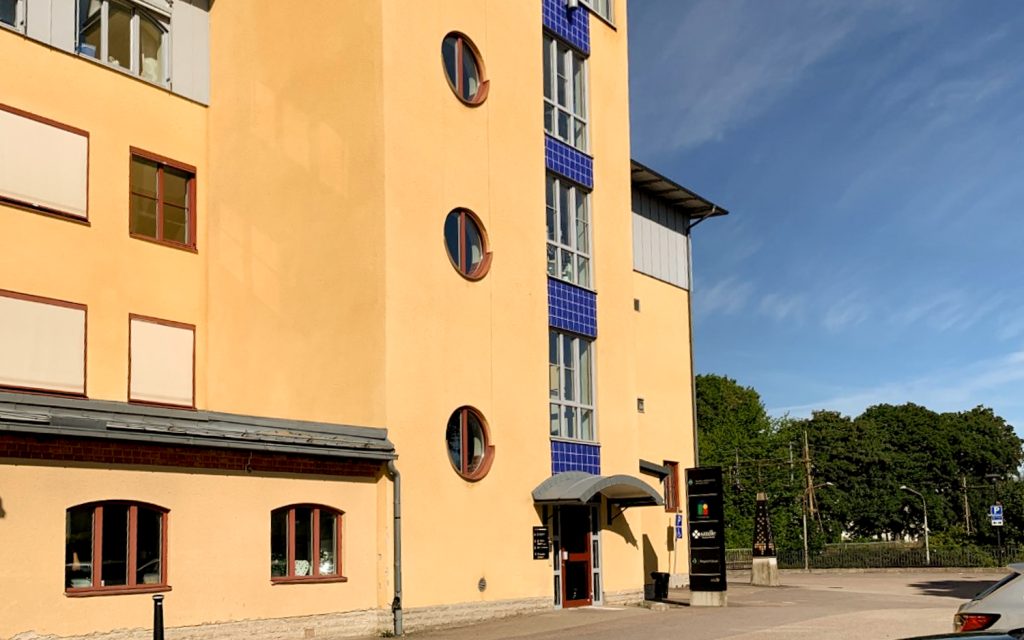 Sidoexteriör av Smile Tandvård i Kumla, med en distinkt gul byggnad med rundade fönster och blåa accenter.
