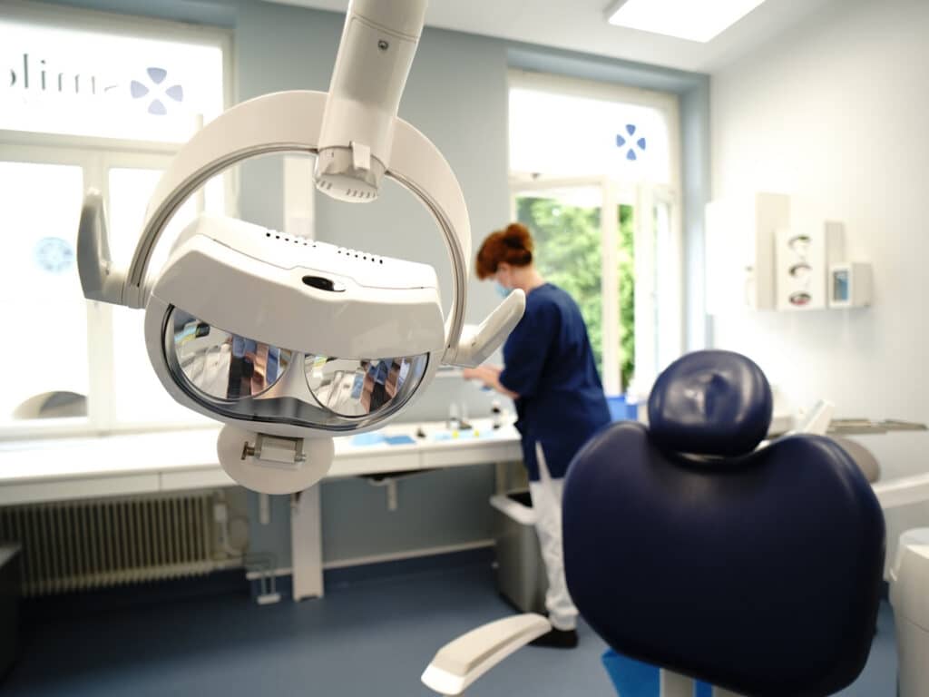 Behandlingsrum hos Smile Tandvård Norrköping med en tandläkarstol och en tandläkare som förbereder utrustning.
