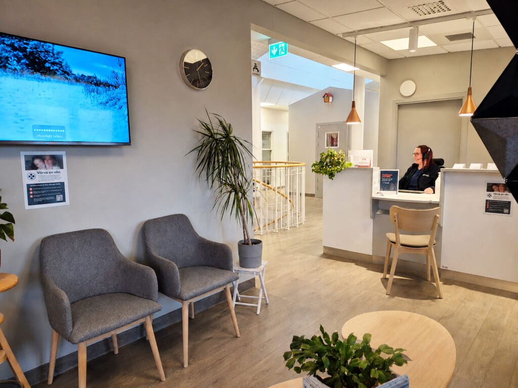 Bild på väntrum hos Smile Sandviken tandläkare med går stolar, bor med växt och välkomnande reception.