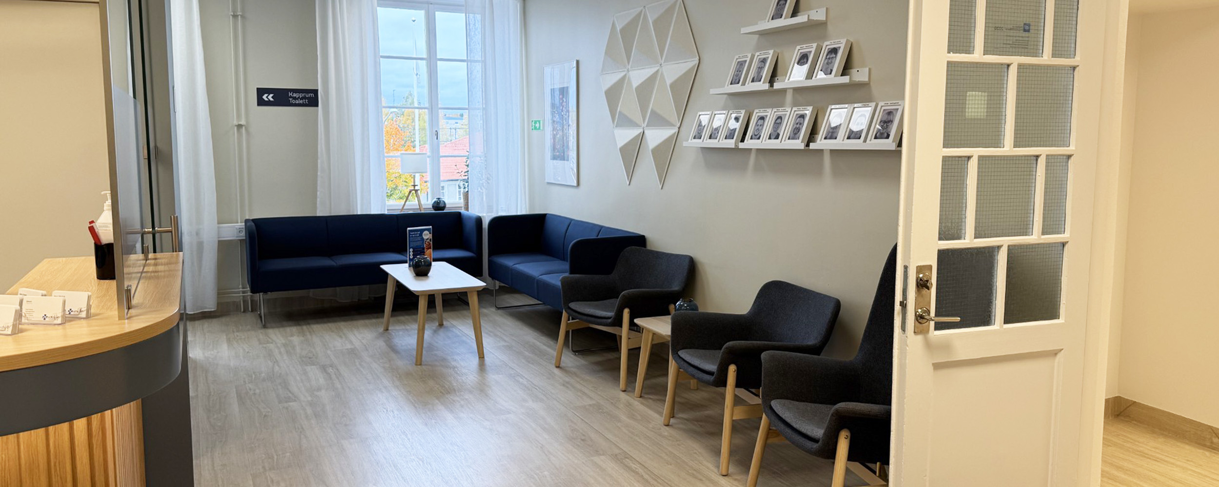En bild av entrén till tandvårdskliniken Smile Tandvård Bollnäs, belägen i en ståtlig byggnad med ljusbrun fasad. En mörk trätrappa leder upp till kliniken. Det finns snö på marken, vilket antyder att bilden är tagen under vintermånaderna.