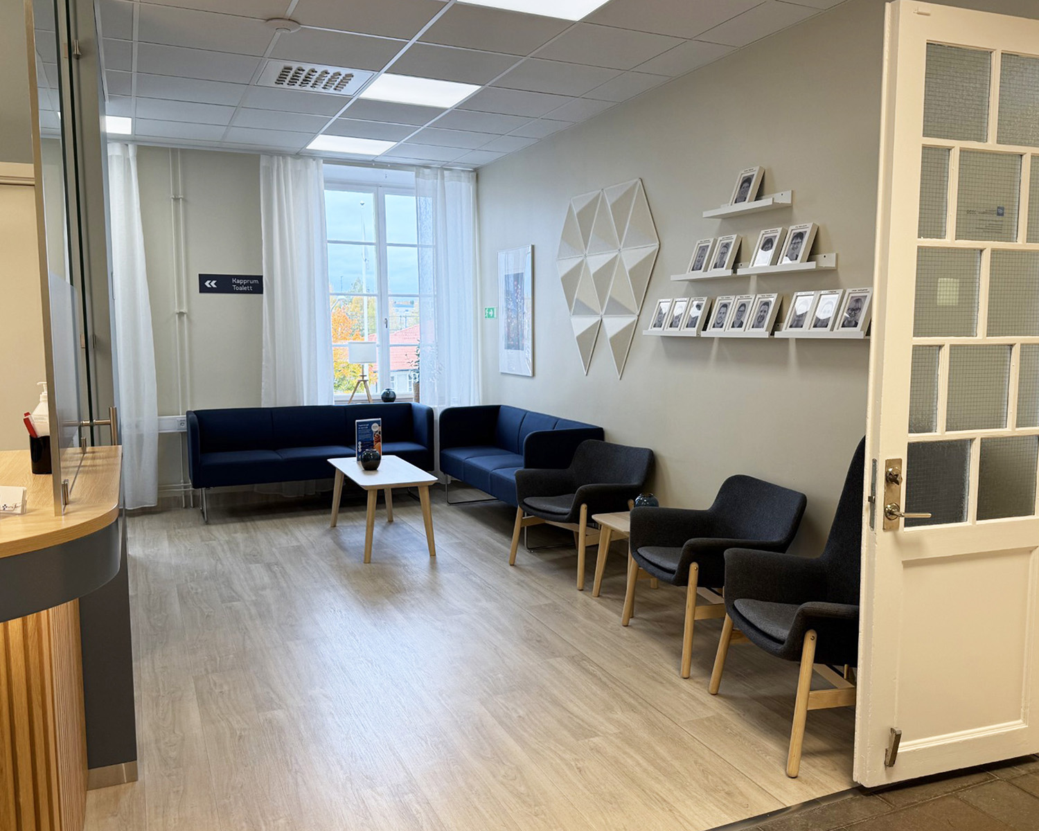 En bild av entrén till tandvårdskliniken Smile Tandvård Bollnäs, belägen i en ståtlig byggnad med ljusbrun fasad. En mörk trätrappa leder upp till kliniken. Det finns snö på marken, vilket antyder att bilden är tagen under vintermånaderna.
