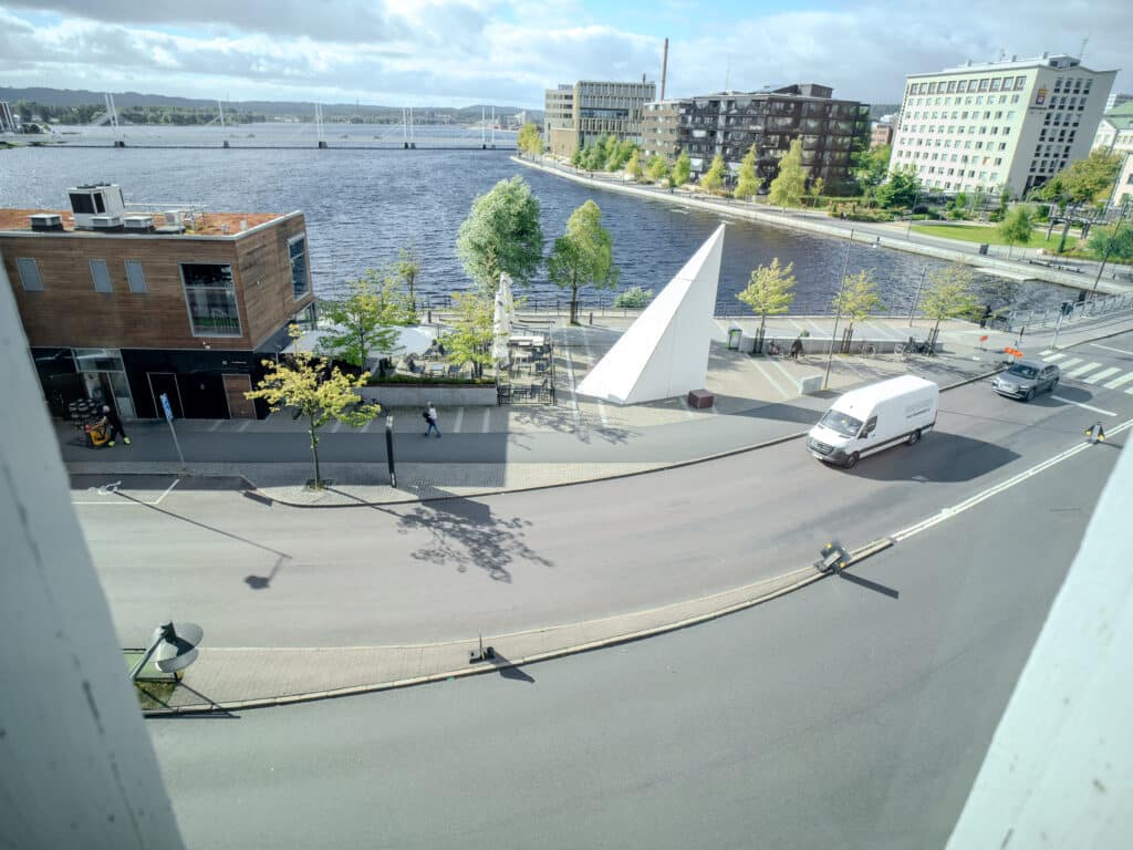 Utsikt över en väg och bro vid vattnet från Smile Tandvård, med omgivande byggnader och grönska i bakgrunden.