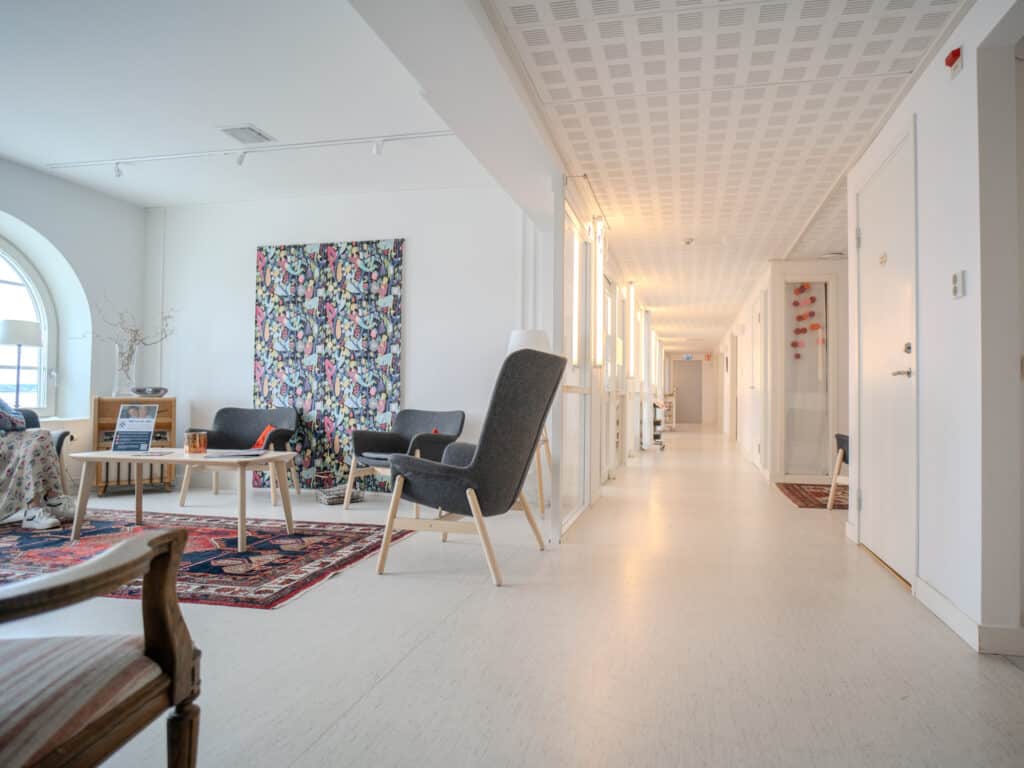Väntrum på Smile Tandvård Lysekil med moderna stolar, konst på väggen och en lång ljus korridor som leder till behandlingsrum.