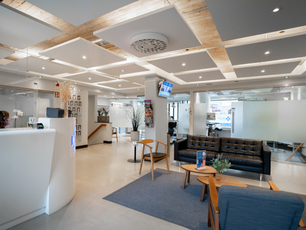 Väntrum på Smile Tandvård Malmö City med modern och stilren inredning. Svart skinnsoffa, träbord med växter och en ljus, inbjudande atmosfär.