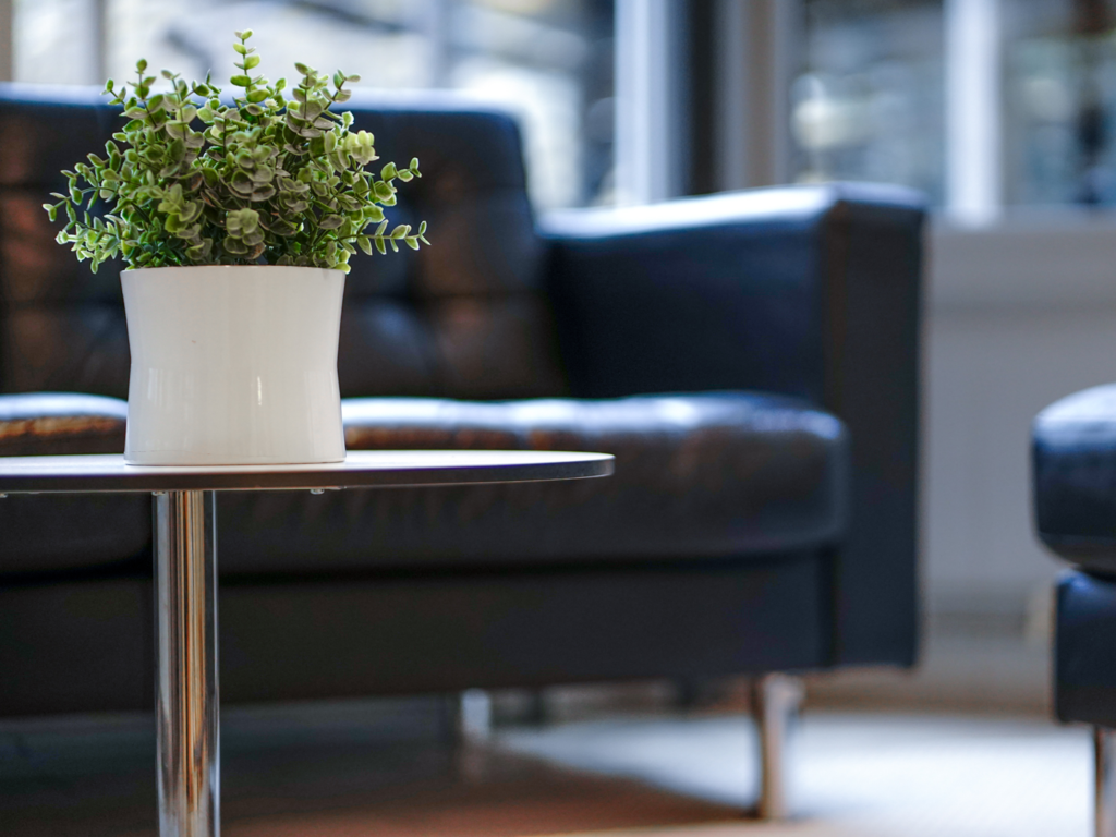 Väntrum på Smile Tandvård Malmö City – Närbild på en sittplats med en svart fåtölj, ett bord och en grön växt som skapar en harmonisk miljö.