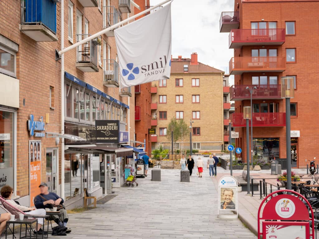 Utsikt över gatan i Mölndal där Smile Tandvårdsklinik är belägen, med klinikens skylt synlig och stadsmiljö i bakgrunden.