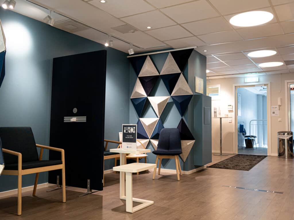 Modernt och inbjudande väntrum på tandklinik med geometriska former på väggen och bekväma sittplatser.