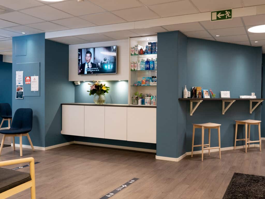 Väntområde på vår tandklinik i Mölndal med bekväma stolar, en receptionsdisk och en hylla med broschyrer och informationsmaterial.