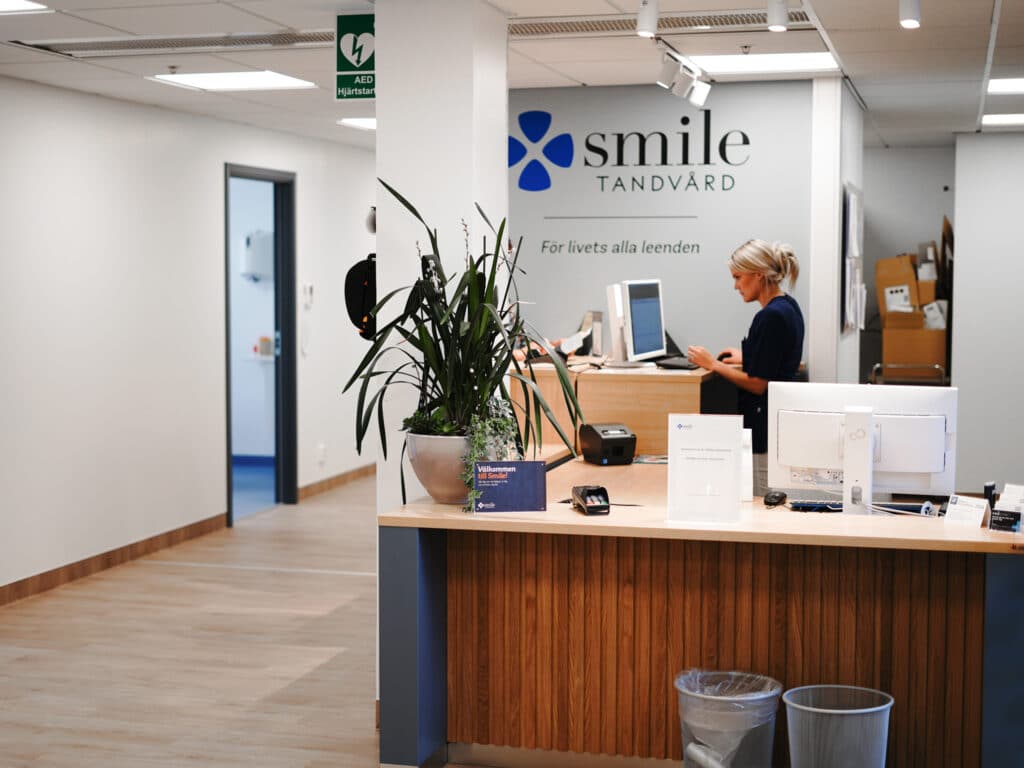 Receptionen hos Smile Tandvård med en receptionist som hjälper en patient vid disken.