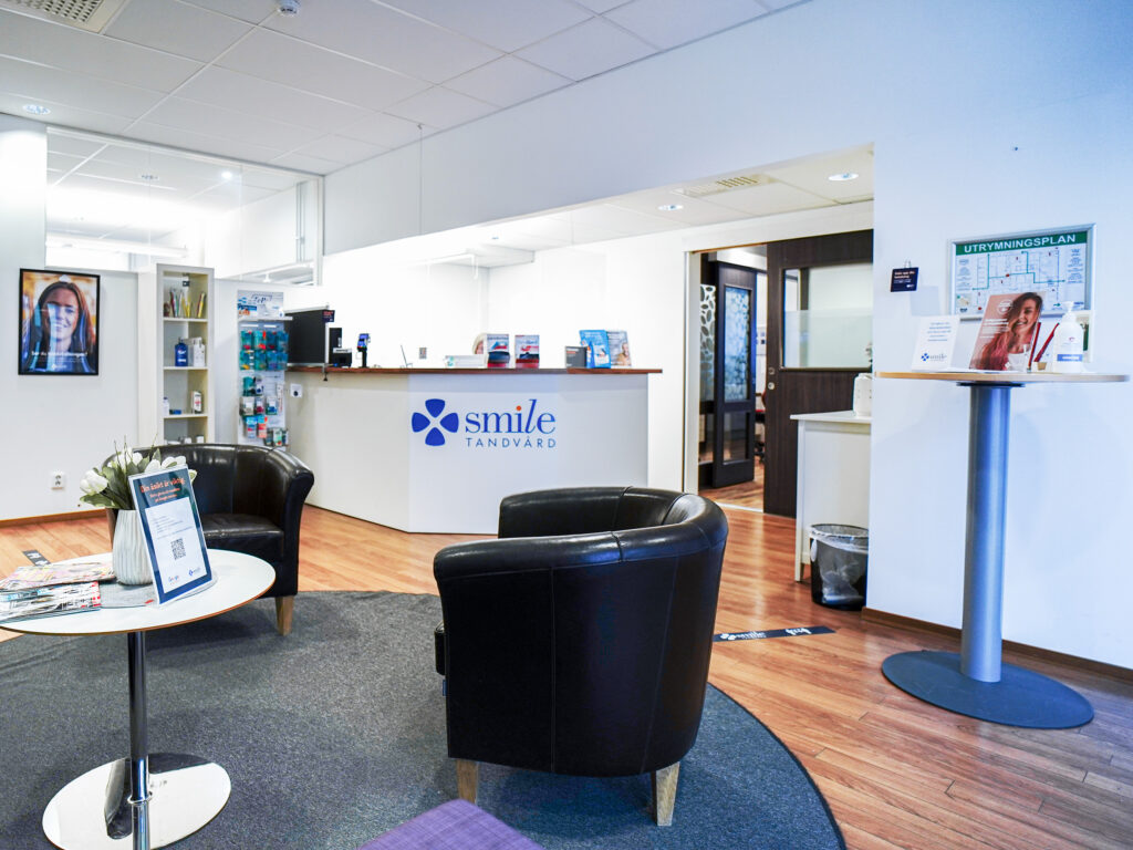 Väntrum hos Smile Tandvård Piteå med bekväma svarta fåtöljer och en receptionsdisk i bakgrunden.