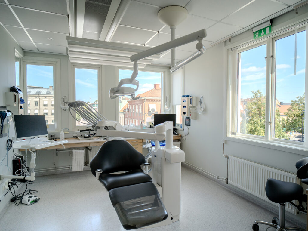 Behandlingsrum på Smile Tandvård med modern utrustning, tandläkarstol och stora fönster som släpper in naturligt ljus med utsikt över staden.