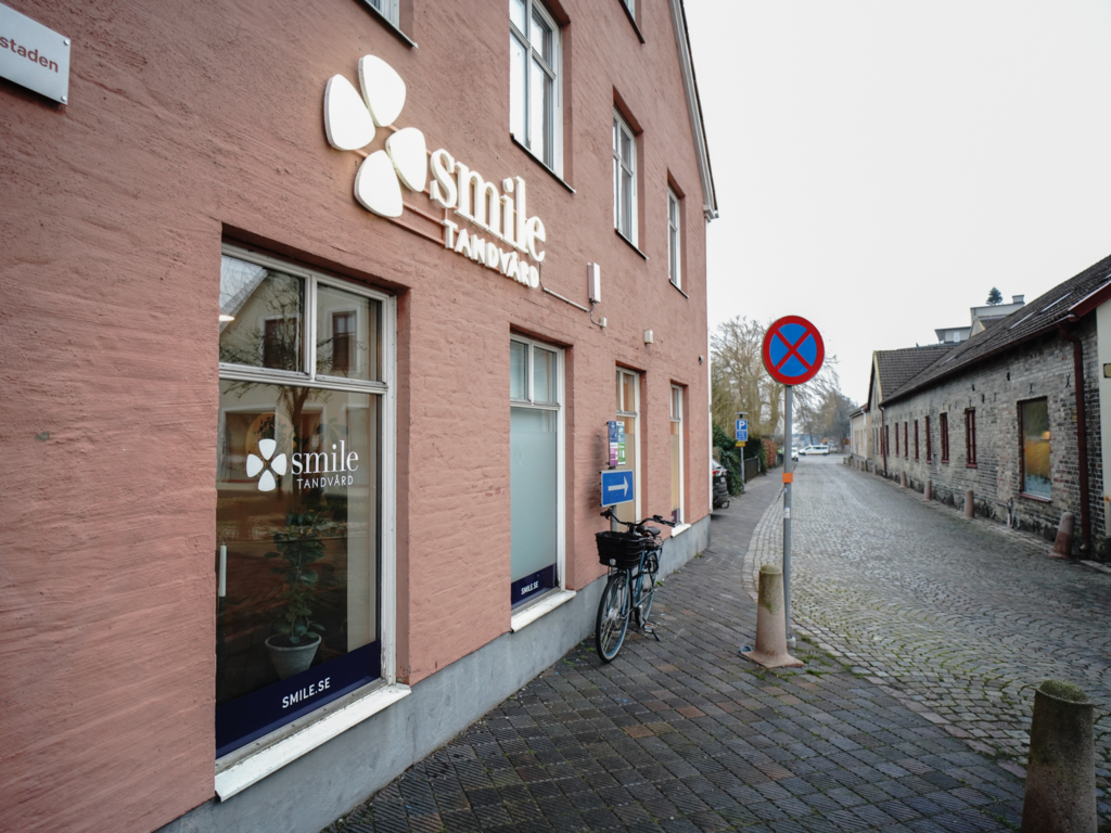 Entré till Smile Tandvård Trelleborg – Klinikingång med tydlig skyltning och glasdörr, omgiven av en charmig stadsmiljö.