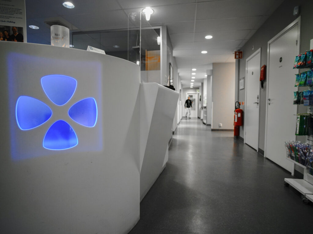 Reception och korridor på Smile Tandvård Trelleborg – Modern och stilren interiör med vit receptionsdisk och blå belysningsdetaljer.