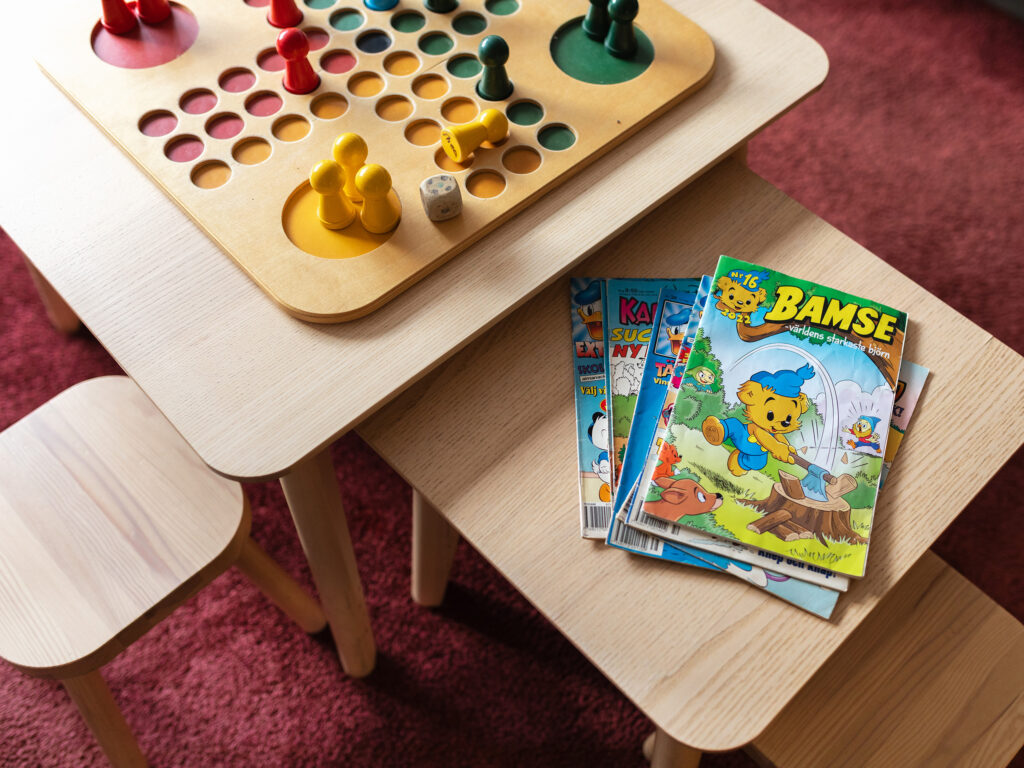 Litet bord med sällskapsspel, snacks och färgglada spelpjäser för barn som ska på tandläkarbesök.