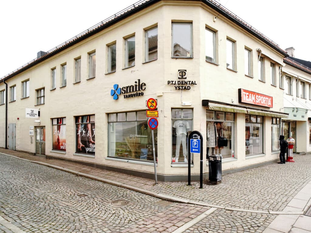 Fasad av Smile Tandvård Ystad – Charmig hörnbyggnad i centrala Ystad med stora fönster och tydlig klinikskyltning, belägen vid kullerstensgata.