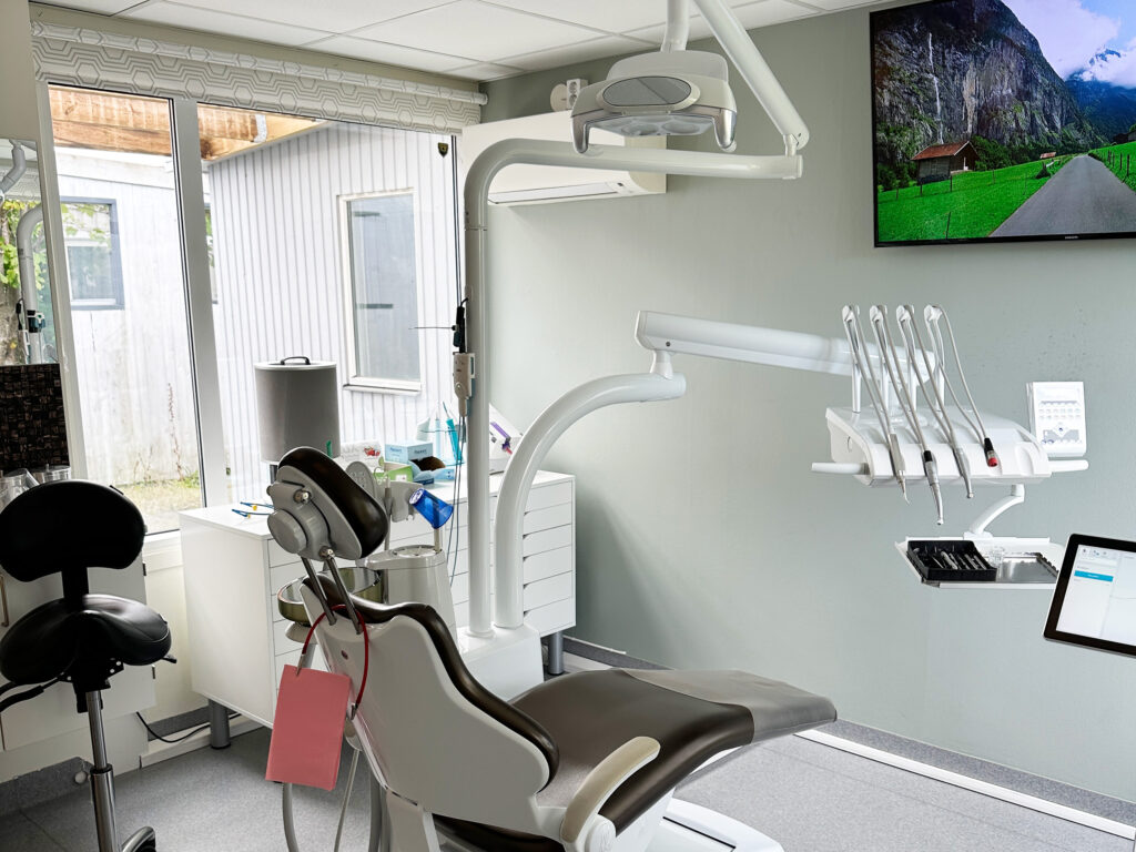 "Behandlingsrum hos Smile Tandvård med tandläkarstol, medicinsk utrustning och ett stort fönster som släpper in naturligt ljus.