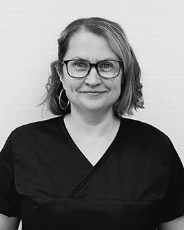 Porträtt av en leende tandläkare i arbetskläder, redo att ge professionell tandvård.
