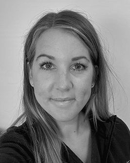Porträtt av en leende kvinna med långt, rakt hår. Bilden är i svartvitt och tagen mot en ljus bakgrund.