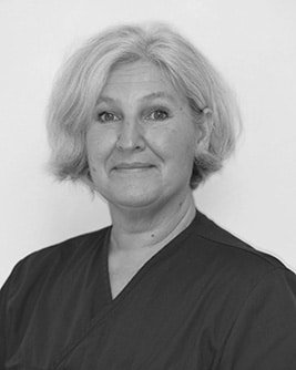 Svartvitt porträtt av en medarbetare med ljust hår. Personen bär en mörk tröja och tittar mot kameran mot en ljus, neutral bakgrund.